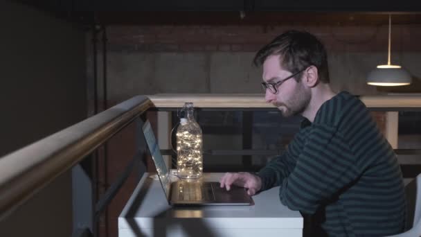 Der bärtige Hipster arbeitet im Coworking Space an einem Startup-Projekt. Mann mit Brille und Laptop im Büro - Filmmaterial, Video