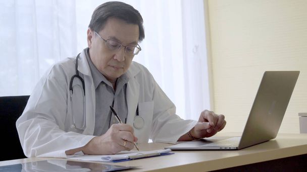 Lékař pracující s údaji o zdravotním stavu pacientů v nemocniční kanceláři. - Fotografie, Obrázek