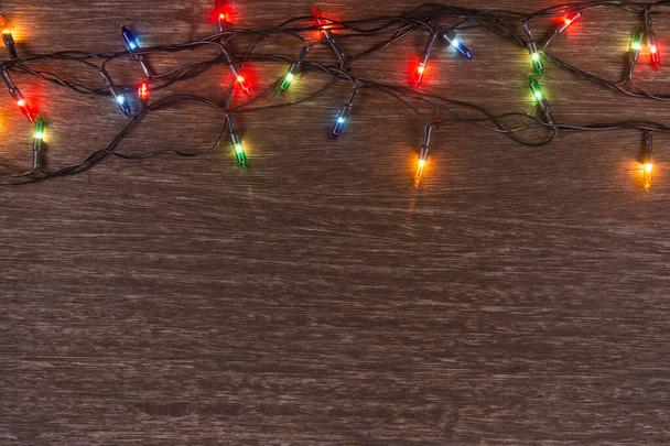 Światła świąteczne na ciemnym drewnianym tle. Wesołych Świąt i  - Zdjęcie, obraz