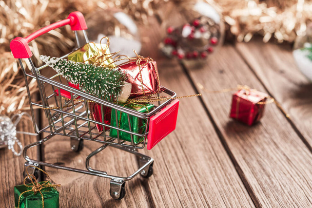 Nákupní košík s vánoční stromeček a miniaturní dárkové krabice na wo - Fotografie, Obrázek