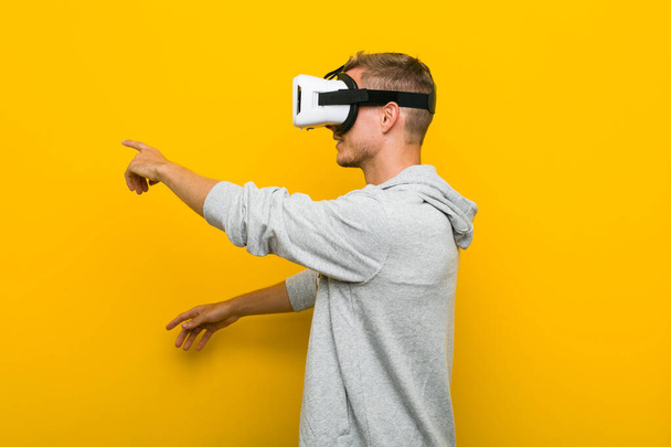 Молодий білий чоловік використовує окуляри віртуальної реальності
 - Фото, зображення