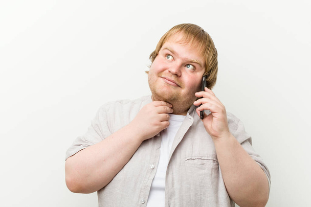 Caucásico más hombre de tamaño llamando por teléfono mirando hacia los lados con expresión dudosa y escéptica
. - Foto, Imagen