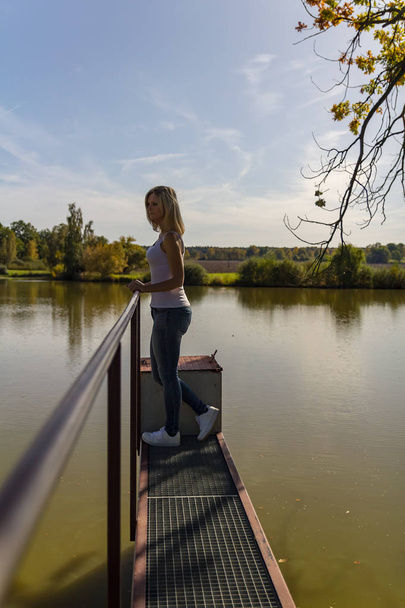 Ritratto di bellezza giovane donna da lato in piedi sul pontile dello stagno
, - Foto, immagini