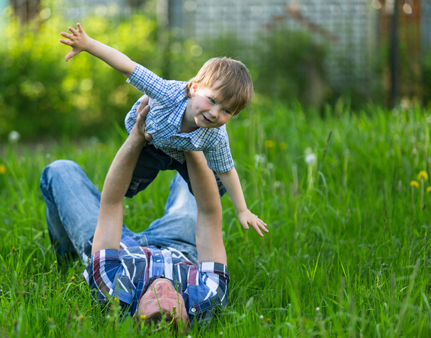 Ojciec gra z jego małym synem w trawie - Zdjęcie, obraz