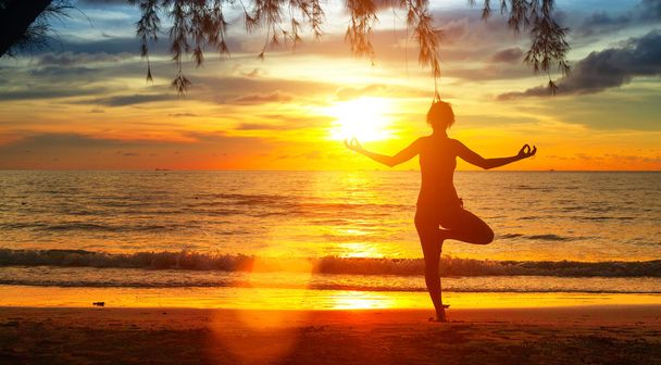 junge Frau praktiziert Yoga am Meer bei Sonnenuntergang - Foto, Bild