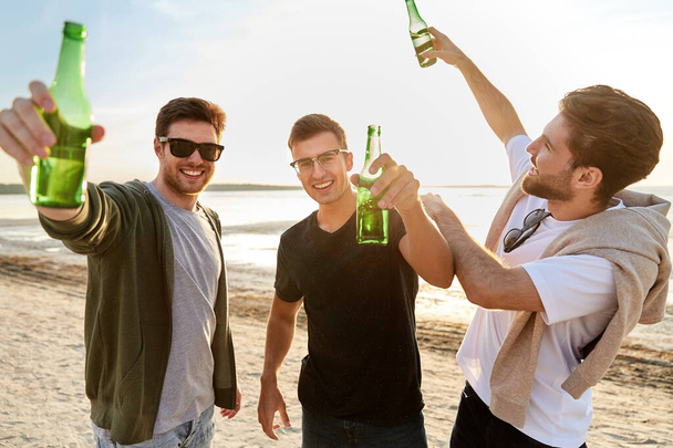 young men toasting non alcoholic beer on beach - Valokuva, kuva