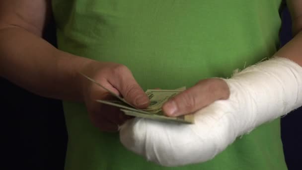 Un homme avec un bras dans un plâtre garde l'argent du coût et des dépenses des soins médicaux d'urgence dans un hôpital
 . - Séquence, vidéo
