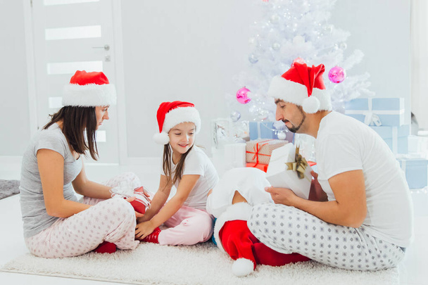 Family exchanging gifts in front of Christmas tree - Photo, image