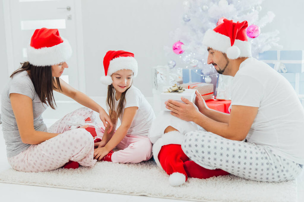 Young family on Christmas morning exchanging presents and enjoying their time together - Photo, image