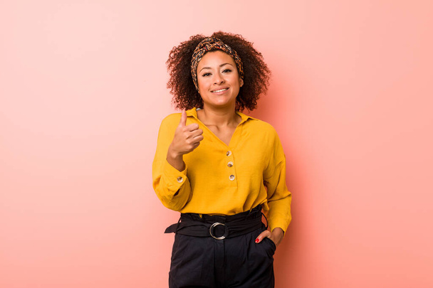 Young african american woman against a pink background smiling and raising thumb up - Foto, Imagen