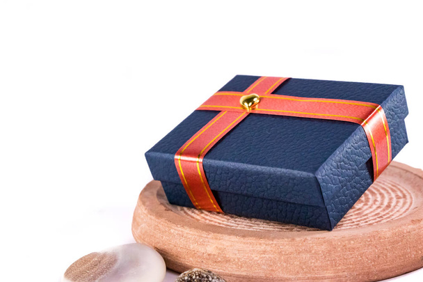 Díszített kék ajándék doboz piros szalaggal és arany szív fehér alapon Valentin napi ajándék koncepció - Fotó, kép