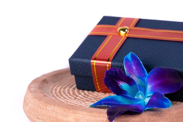 Крупним планом знімок прикрашеної синьої подарункової коробки зі стрічкою та синьою квіткою орхідей на білому тлі
 - Фото, зображення