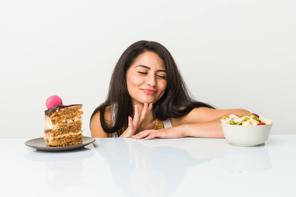 junge hispanische Frau hat die Wahl zwischen Kuchen oder Obstschale - Foto, Bild