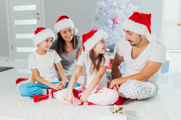 Happy parents and children exchanging gifts near Christmas tree at home - Foto, Imagen