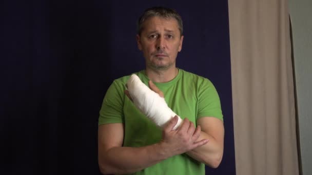 Een man krabt zijn arm in een gips. . - Video