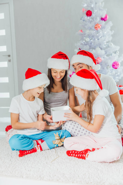 Happy family in Christmas morning opening present in home front of Christmas tree - Foto, Imagen
