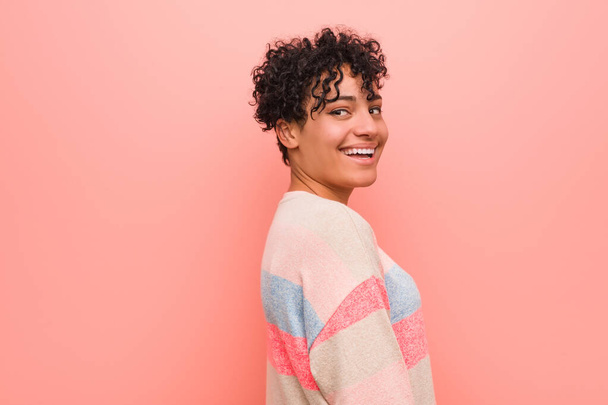 Jeune femme adolescente afro-américaine mixte regarde de côté souriant, gai et agréable
. - Photo, image