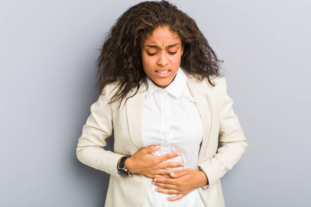 Joven mujer de negocios afroamericana enferma, que sufre de dolor de estómago, concepto de enfermedad dolorosa
. - Foto, imagen