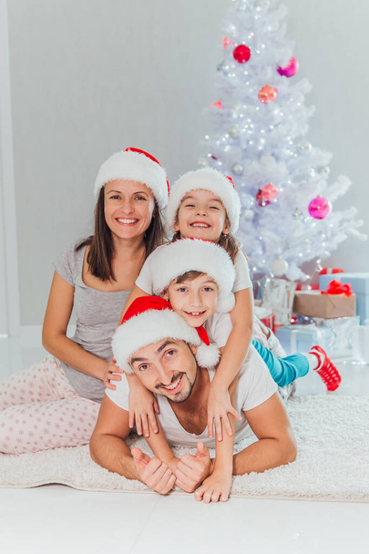 happy family lies on the floor near the festive Christmas tree, near Christmas gifts - Foto, imagen