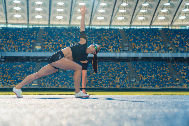 Young female runner stretching arms and legs before running - Foto, afbeelding