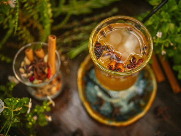 Hot mulled wine in a glass goblet with cinnamon sticks. Vegetation around - Foto, Bild