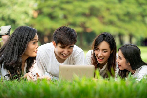 Team of young students studying in a group project in the park of university or school. Happy learning, community teamwork and youth friendship concept. - 写真・画像