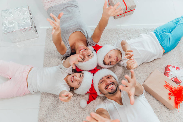 Merry Christmas and Happy New Year Top view of beautiful family is waiting for the New Year together while lying near beautiful Christmas tree at home - Photo, Image