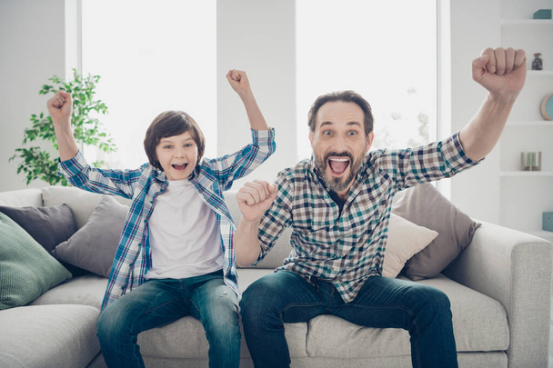 Portrait of two nice attractive cheerful cheery glad guys dad and son watching sports on TV having fun at light white modern style interior house living-room indoors - Zdjęcie, obraz