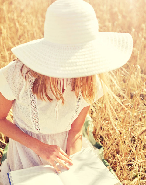 close up of woman reading book on cereal field - Foto, imagen