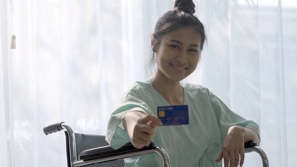 Happy patient hold credit card and smile while sitting on wheelc - Photo, Image