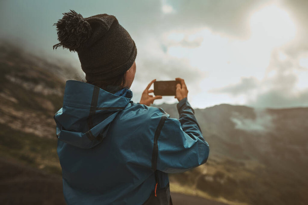 A hiker girl take a pictures on a smartphone in the mountains - Foto, Imagem