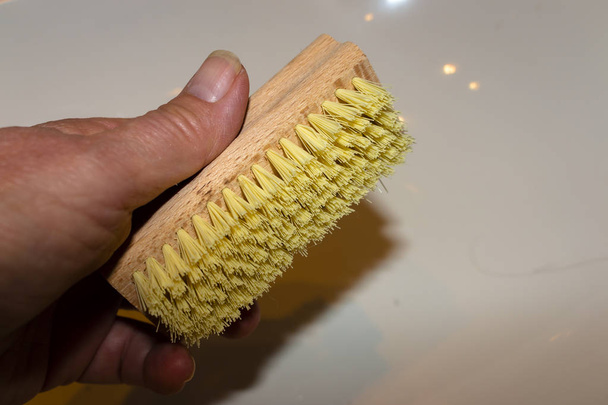 Mão está segurando uma escova de madeira com cerdas amarelas na frente de
  - Foto, Imagem