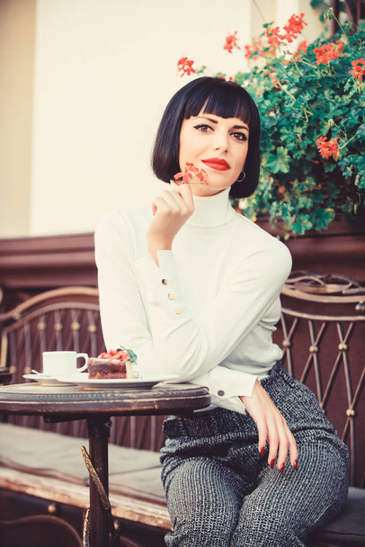 Gourmet concept. Pleasant time and relaxation. Delicious gourmet cake. Pamper yourself. Girl relax cafe with cake dessert. Woman attractive elegant brunette eat gourmet cake cafe terrace background - Photo, Image