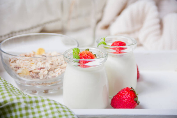 Two portions natural homemade yogurt in a glass jar with fresh strawberry and muesli nearby - Fotografie, Obrázek