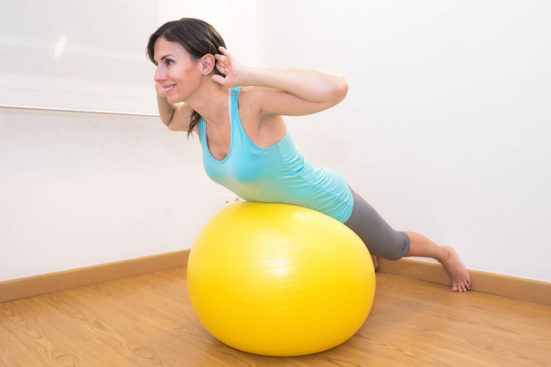 Женщина тренируется с мячом в спортзале. Пилатес женщина делает упражнения в тренажерном зале с фитнес-мяч
. - Фото, изображение