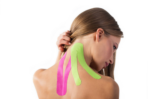 Woman shows kinesio tapes taped to her neck. Isolated on white background. Sport and healthy lifestyle concept - Foto, Bild