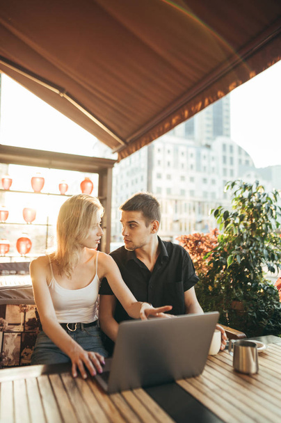 Young guy and attractive girl sitting on terrace in restaurant w - Foto, Bild
