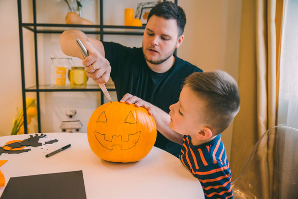 young father with toddler son making jack pumpkin head for halloween holiday - Φωτογραφία, εικόνα