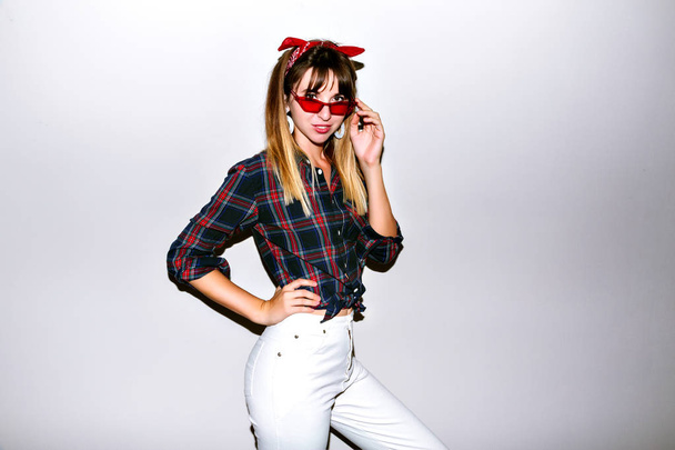 Young beautiful woman posing in studio in sunglasses - Foto, imagen