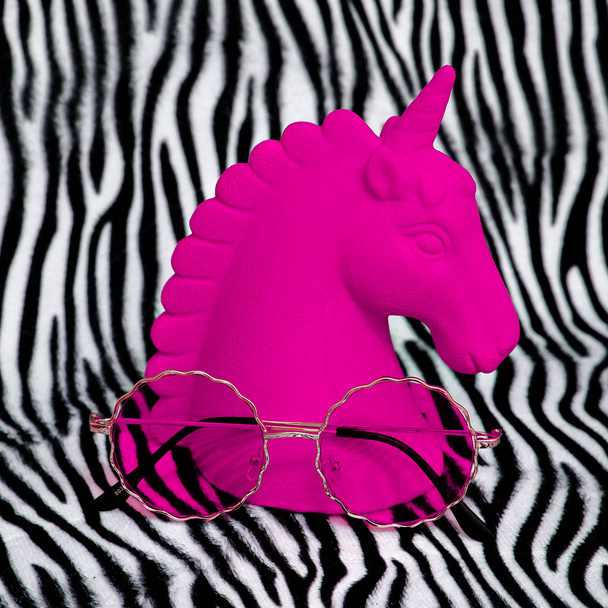 Pink unicorn souvenir and stylish sunglasses on zebra print back - Foto, Imagem