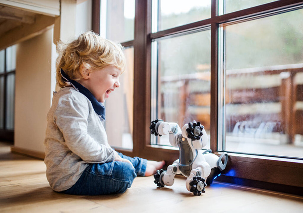 Egy aranyos kisgyerek otthon ül, robotkutyával játszik.. - Fotó, kép