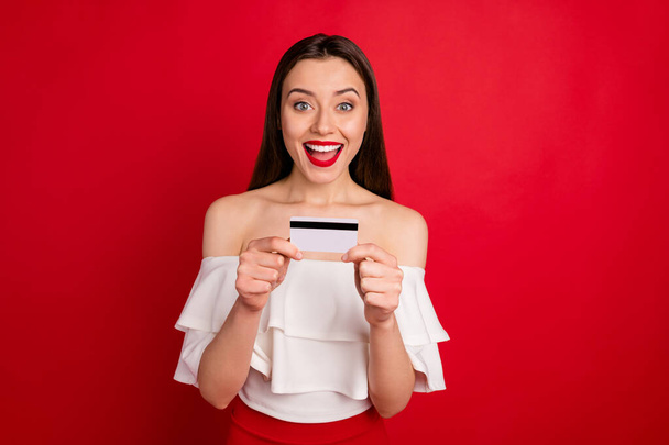 Portrait of sweet lady holding plastic card screaming shouting dressed white blouse top isolated over red background - Foto, imagen