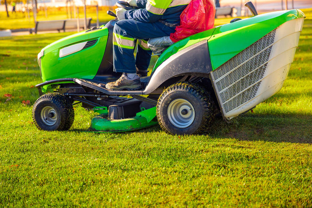 Trabajador jardinero en cortacésped tractor corta hierba verde
 - Foto, Imagen