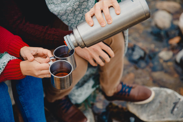 Man pours hot tea girl in metal mug. Concept camping dishes - Photo, Image