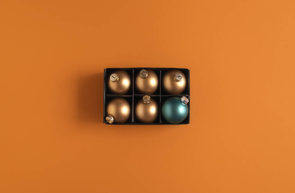 Arany karácsonyi labdák egy dobozban és csak egy kék karácsonyi csecsebecse - Fotó, kép