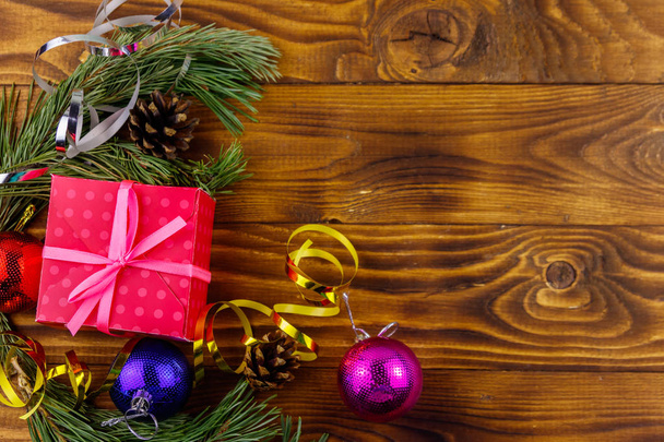 Composición navideña con ramas de abeto, caja de regalo y decoraciones navideñas en mesa de madera. Vista superior, espacio de copia - Foto, Imagen