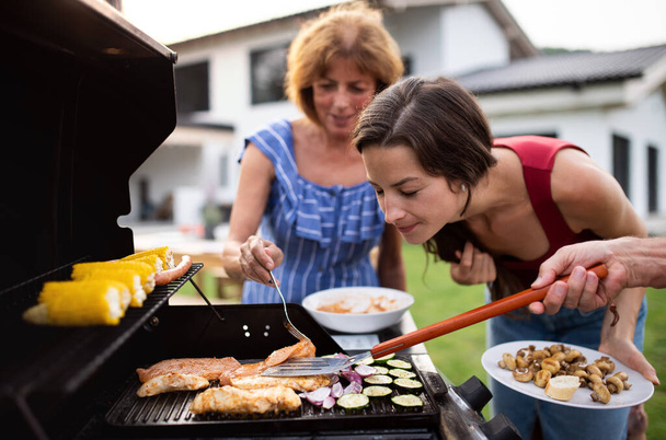 Portrait of multigeneration family outdoors on garden barbecue, grilling. - Foto, afbeelding
