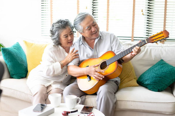 Lovers in a living room. Beautiful senior Asian couple sitting o - 写真・画像