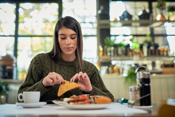 Attractive brunette sitting in restaurant in morning and eating breakfast. - Fotografie, Obrázek