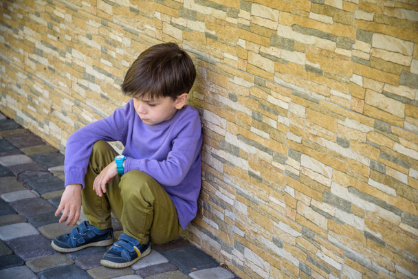 Маленький мальчик, грустный сидя один в школе, прячет лицо. Изоляция
 - Фото, изображение